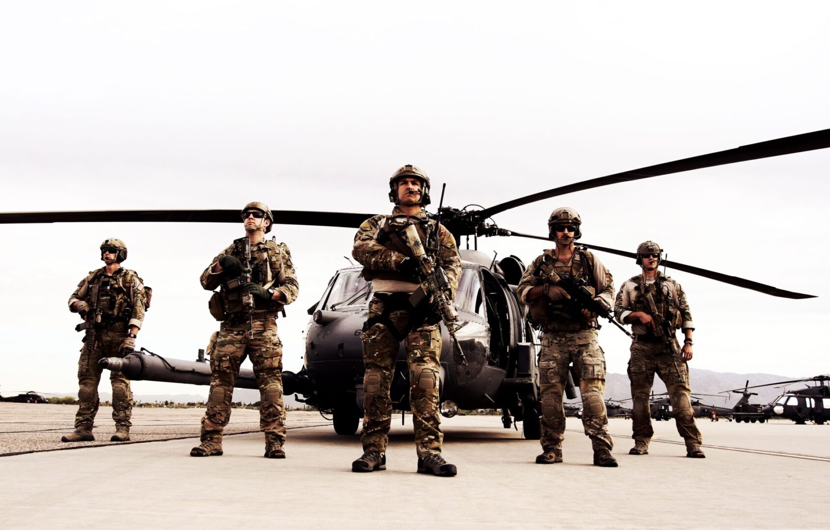 A group of soldiers standing in front of an army helicopter.